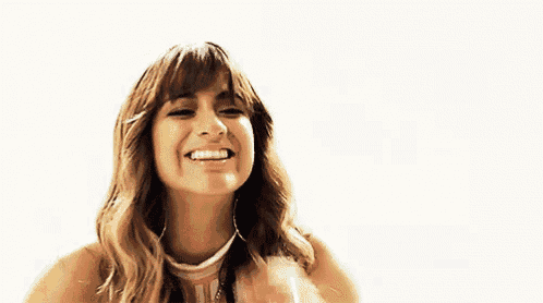 a woman is smiling and touching her face with her hand on a white background .