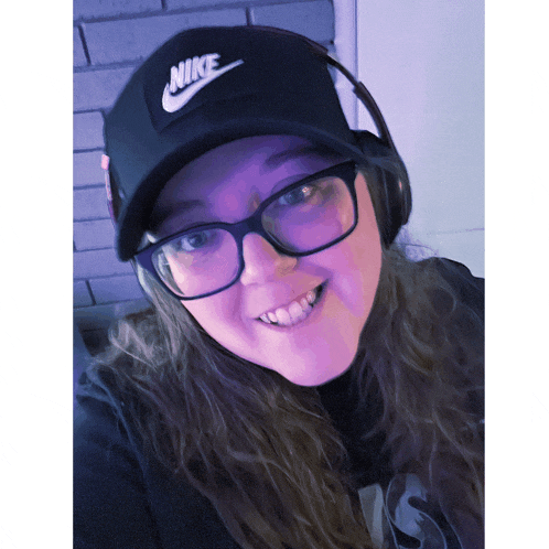 a woman wearing glasses and a nike hat smiles