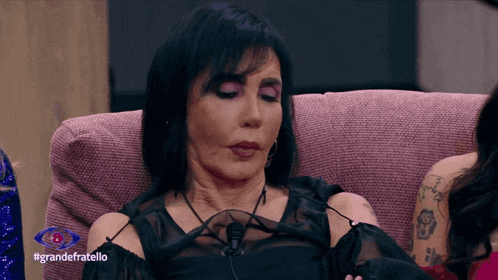 a woman is sitting on a couch with the hashtag grandefratello