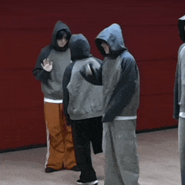 a group of people wearing hoodies are standing in a room
