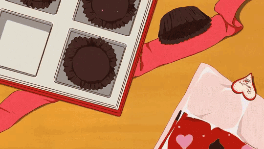 a box of chocolates sits on a table next to a valentine 's card