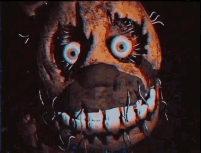 a close up of a cartoon character 's face with big eyes and sharp teeth in the dark .