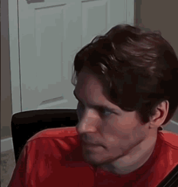 a close up of a man 's face with a red shirt on