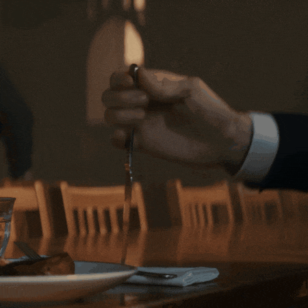 a man in a suit is cutting a piece of meat with a knife