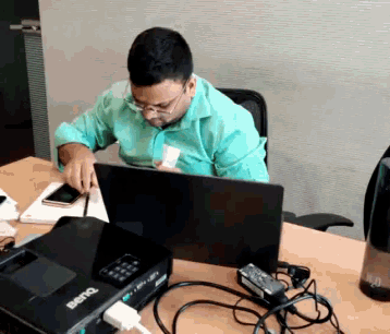 a man is sitting at a desk with a benq projector