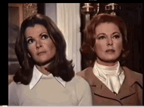 two women are standing next to each other and looking at something