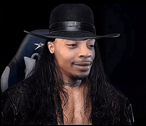 a man with long hair is wearing a black hat