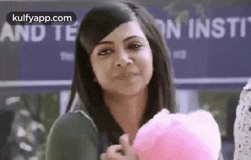 a woman is holding a pink ball of cotton candy and smiling .