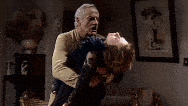 a man is holding a woman upside down in a living room