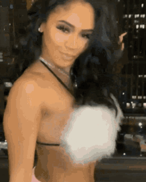 a woman in a bikini top with feathers on it is standing in front of a window and smiling .