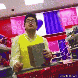 a man wearing glasses and a yellow vest is holding a book in a store