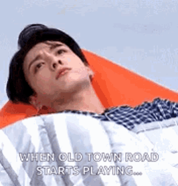 a man is laying on a bean bag chair with a blanket on his head and a quote .