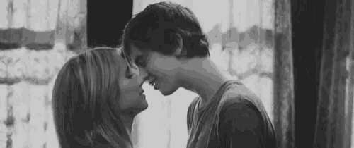 a black and white photo of a man and woman kissing .