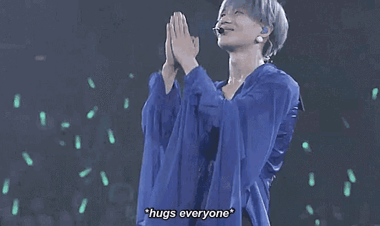 a person in a blue shirt is standing on a stage with their arms outstretched .