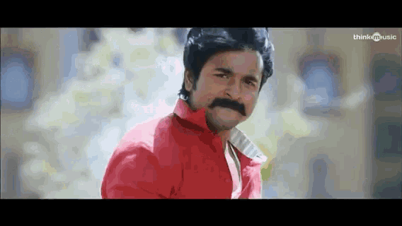 a man in a red shirt with a mustache is looking at the camera .