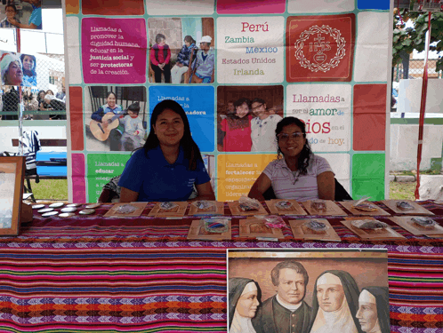 two women sitting at a table in front of a sign that says peru