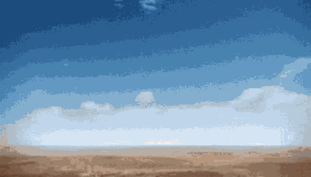 a blue sky with white clouds over a desert