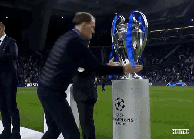 a man is holding a trophy that says champions league