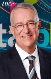 a man in a suit and tie is smiling in front of a sign that says tiktok