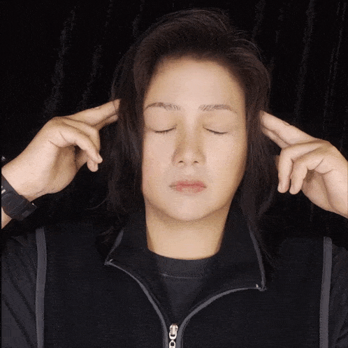 a woman with her eyes closed holds her hands to her ears