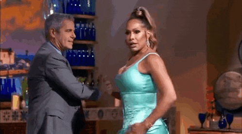 a man in a suit and a woman in a blue dress are dancing together .