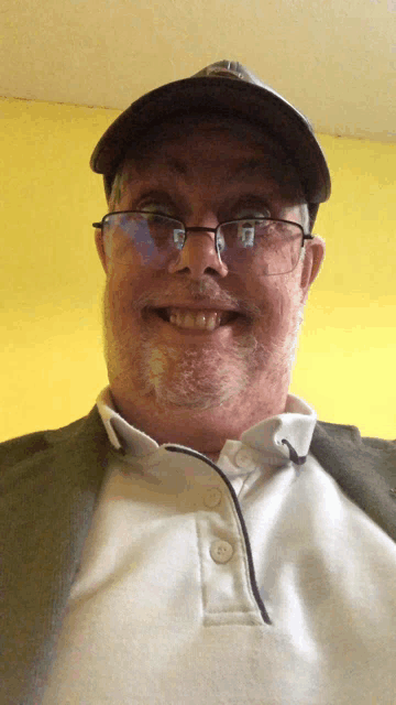 a man wearing glasses and a hat is smiling for a picture