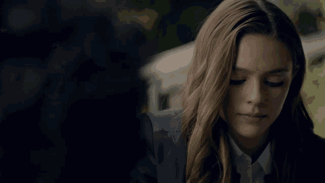 a woman in a suit and white shirt looks down at something