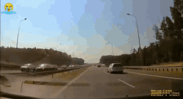 a car driving down a highway with a yellow smiley face on the bottom right