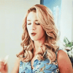 a woman with blonde hair is wearing a blue shirt with a floral pattern .