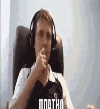 a man wearing headphones is sitting in a chair with his hand in his mouth .