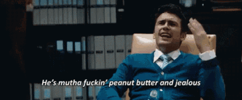 a man in a blue sweater and tie is sitting in a chair and says he 's mutha fuckin '