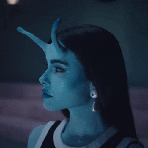 a woman with blue paint on her face is wearing a pair of earrings with the letter p on them