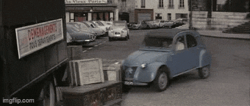 a blue car is driving down a street in front of a sign that says demenagements .