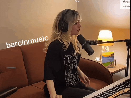 a woman singing into a microphone with barcinmusic written on the bottom right