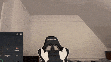 a black and white s-racer gaming chair in front of a computer screen