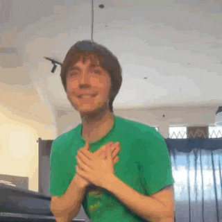 a man in a green shirt is holding his hands to his chest