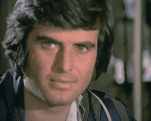 a close up of a man 's face with a blue jacket on