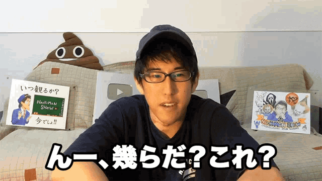 a man wearing glasses and a hat is sitting on a couch in front of a sign that says nakamura show