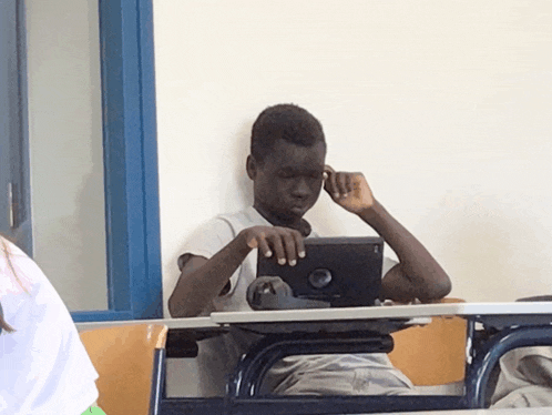 a boy sits at a desk using a tablet with a dell logo on the screen