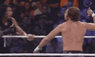 a man without a shirt is standing in a boxing ring with a crowd behind him .
