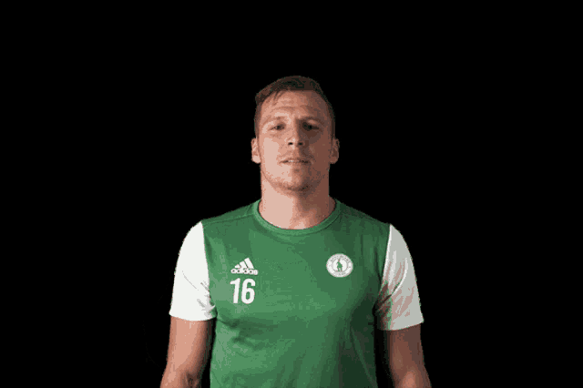 a man wearing a green and white adidas shirt with the number 16 on it