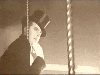a man wearing a top hat is sitting on a carousel .