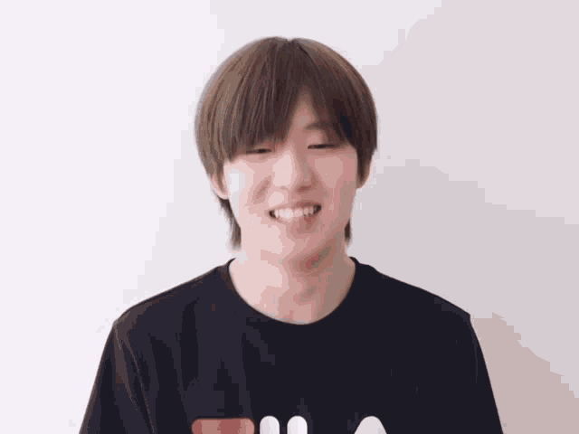 a young man wearing a black fila t-shirt is smiling