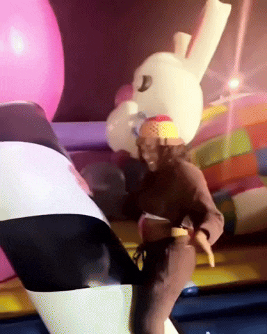 a person in a bunny costume is standing in front of a colorful inflatable bunny