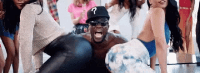 a man wearing a hat with a question mark on it is surrounded by a group of women .