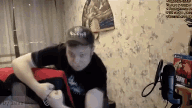 a man wearing a black hat with the word russia on it is sitting on a couch