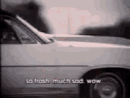 a black and white photo of a car with the words `` so trash much sad wow '' written on it .