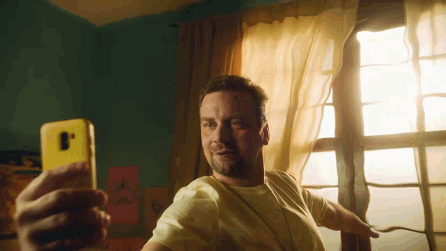 a man taking a picture of himself with a yellow cell phone