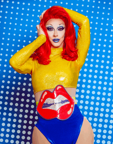 a woman with red hair wearing a yellow top and blue shorts