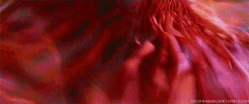 a woman in a red dress is standing in front of a crowd of people .